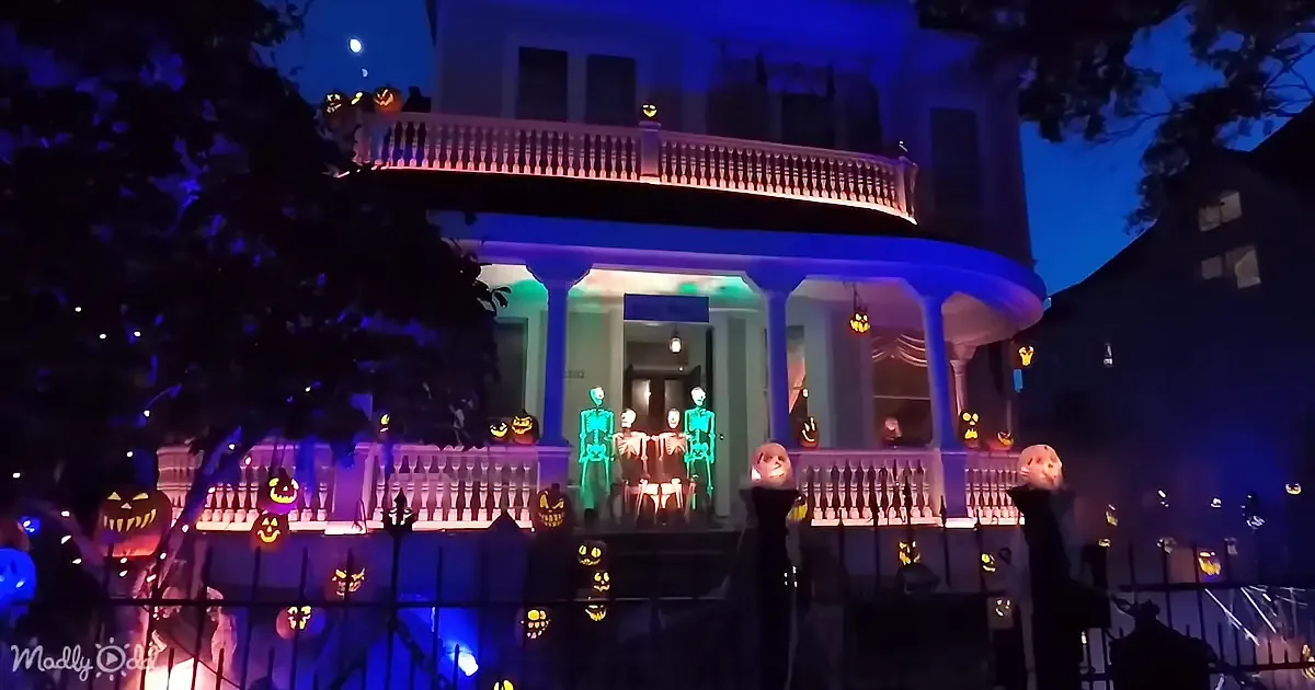 A house decorated for Halloween with glowing pumpkins, skeletons, and colorful lights.