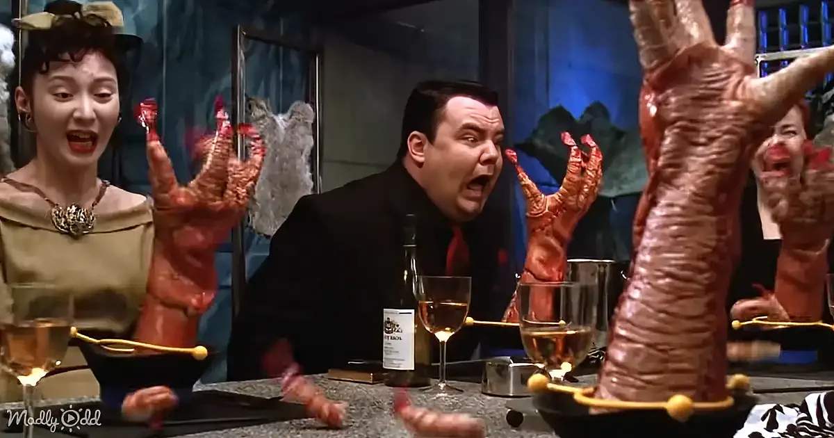 A man in a suit is surrounded by giant, grotesque hands and appears shocked.