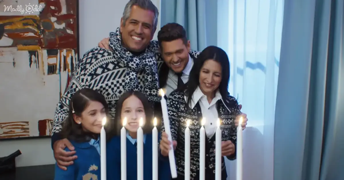 A family of five smiles behind lit candles, celebrating together indoors.