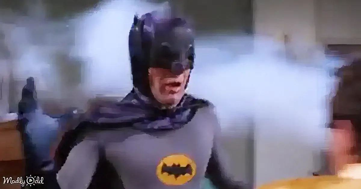 Batman in costume, surrounded by smoke, appears surprised or shocked.