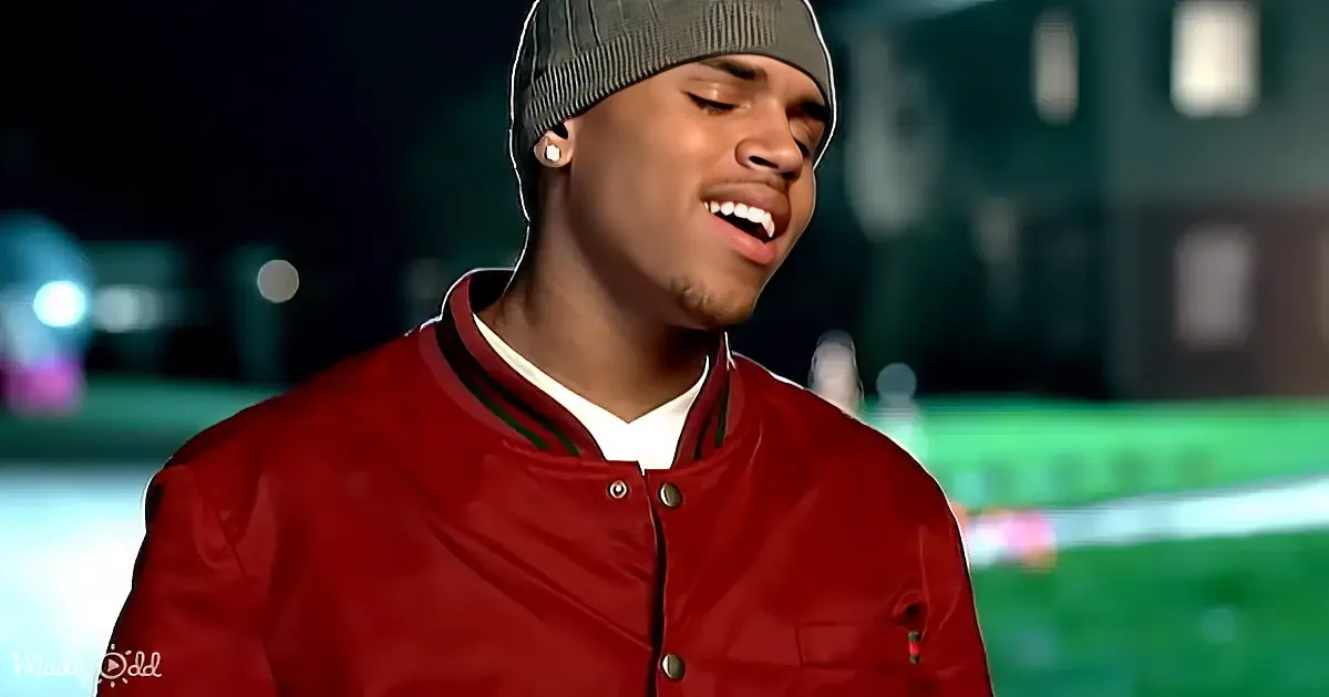 A man in a white suit and tie is singing with his eyes closed and hand raised.