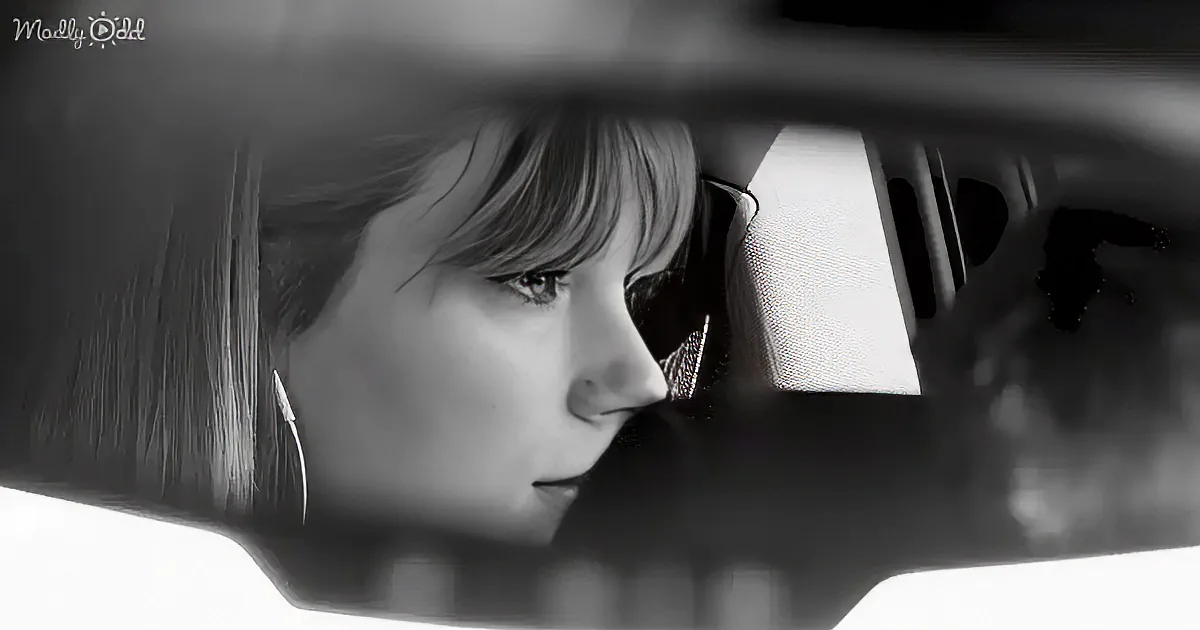 A woman with short hair looks out of a car window, her reflection in the rearview mirror.