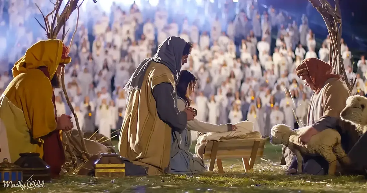 A nativity scene with Mary, Joseph, and baby Jesus surrounded by shepherds and a crowd in white robes.
