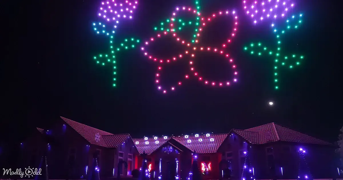 A drone display forms "FROSTY" in lights above a house decorated with holiday lights.