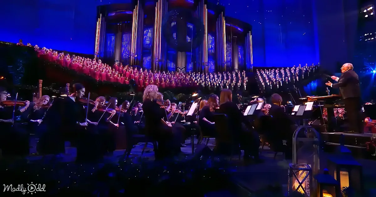 Conductor leads orchestra and choir in a grand performance with blue lighting.
