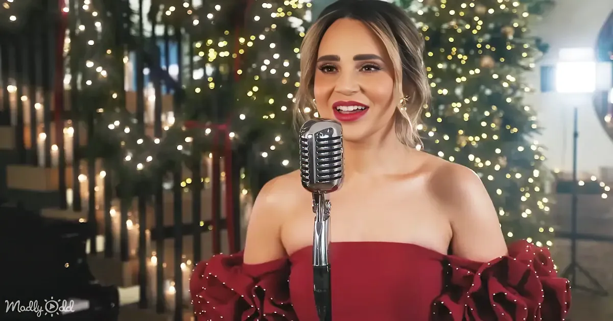 A woman in a red dress sings into a vintage microphone, surrounded by Christmas lights and a festive backdrop.