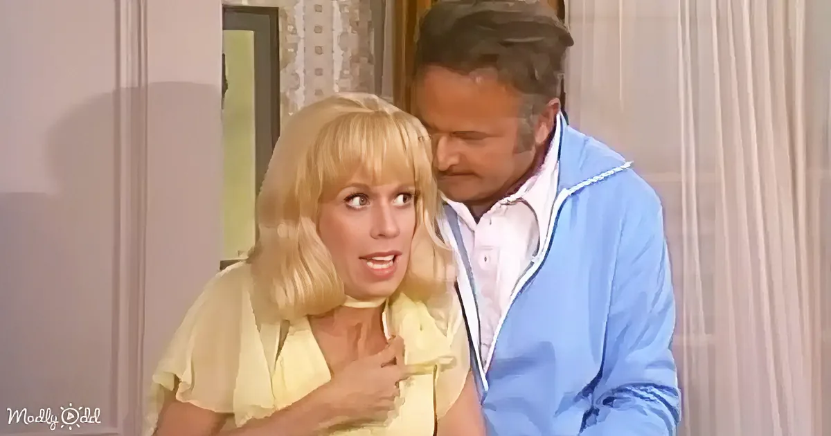 A woman in a yellow top is surprised, with a man in a blue jacket leaning close behind her.