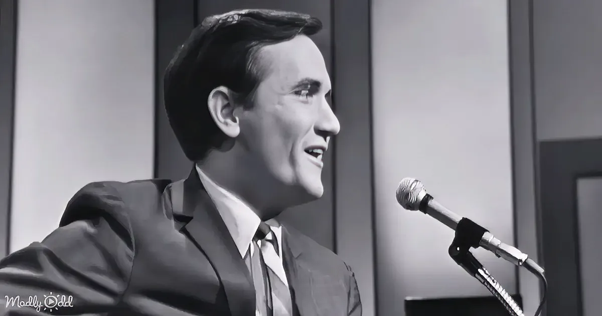A man in a suit sings into a microphone, smiling, in a black-and-white setting.