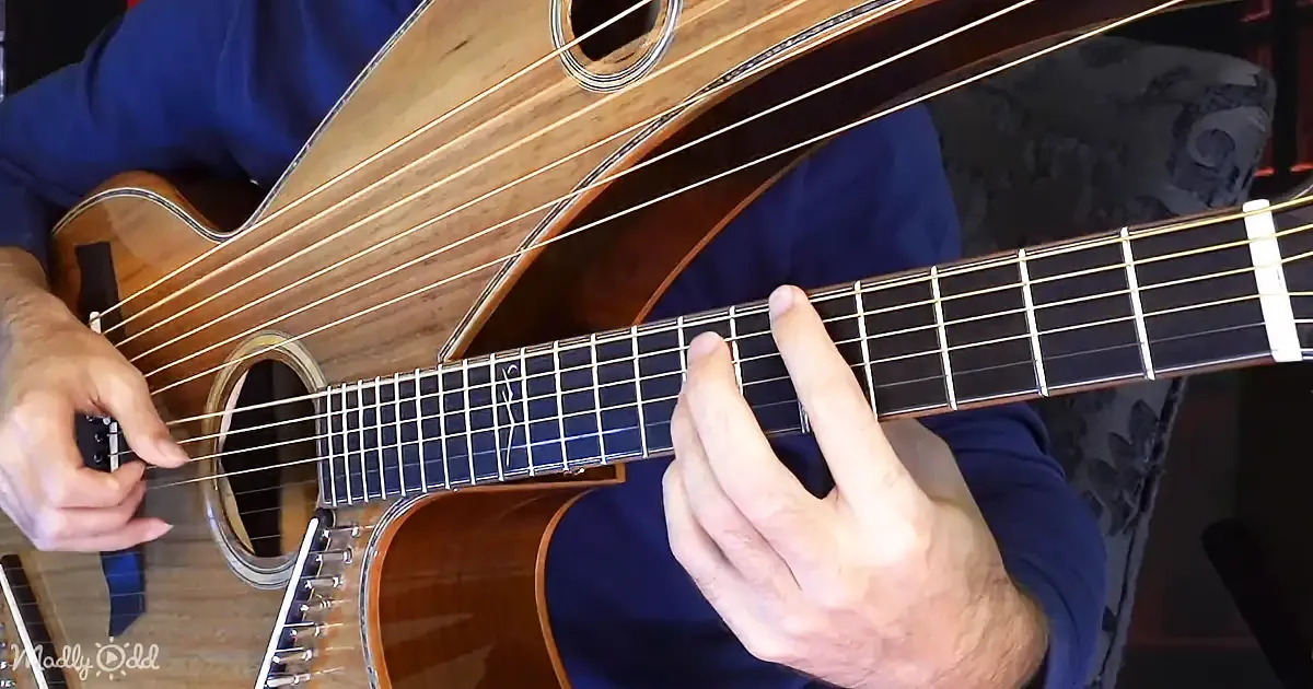 A person plays an acoustic guitar, fingers positioned on the fretboard, with a blue shirt and guitar case visible.