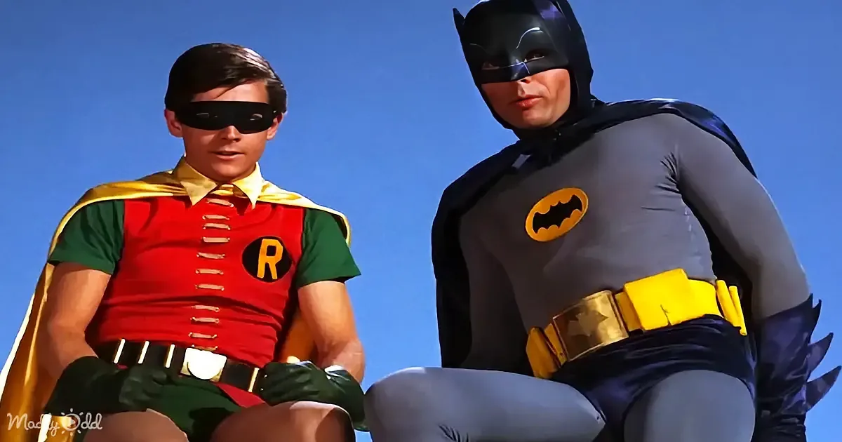 Batman and Robin in their iconic costumes, sitting against a clear blue sky.