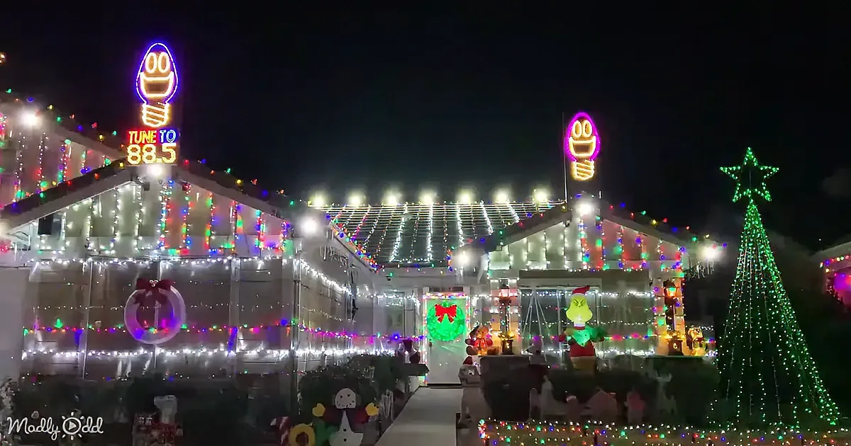A festive house adorned with Christmas lights, decorations, and a Grinch inflatable, illuminated at night.