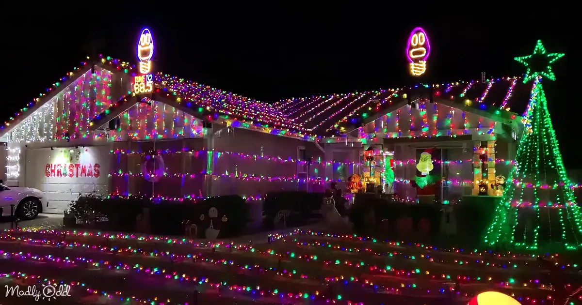 A house adorned with vibrant Christmas lights and festive decorations, including a Grinch figure and a lit-up tree.
