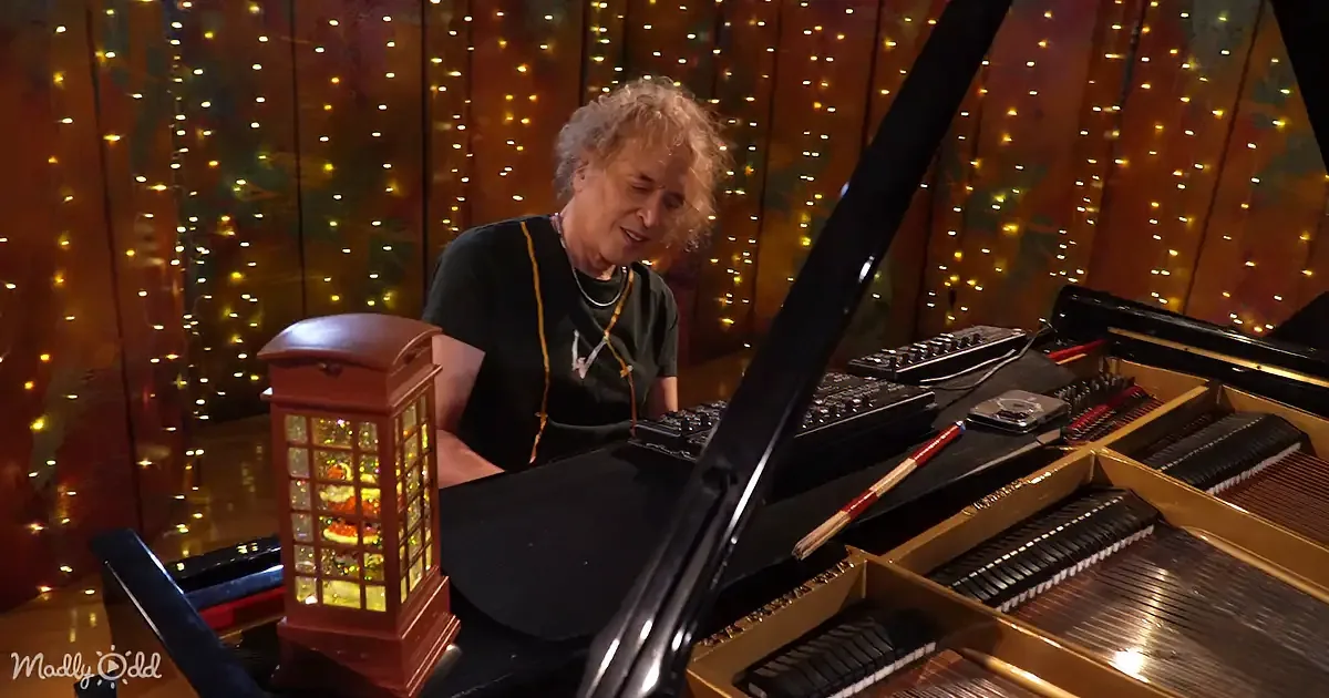 A person sits at a grand piano with a festive background, surrounded by holiday decorations.