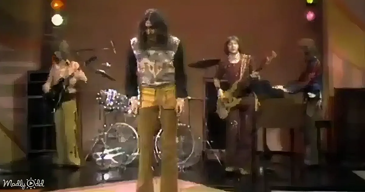 A band member in a colorful outfit stands center stage, surrounded by other musicians playing instruments.