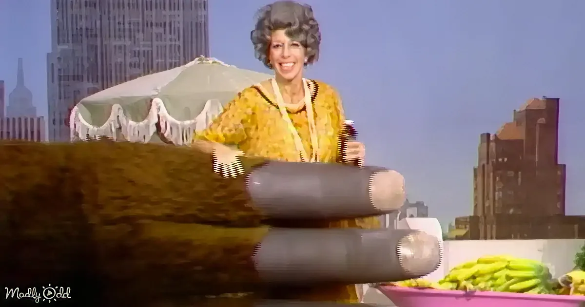 A woman in a yellow patterned shirt is smiling while holding a hairbrush, with a large brown bear's paw in the foreground.