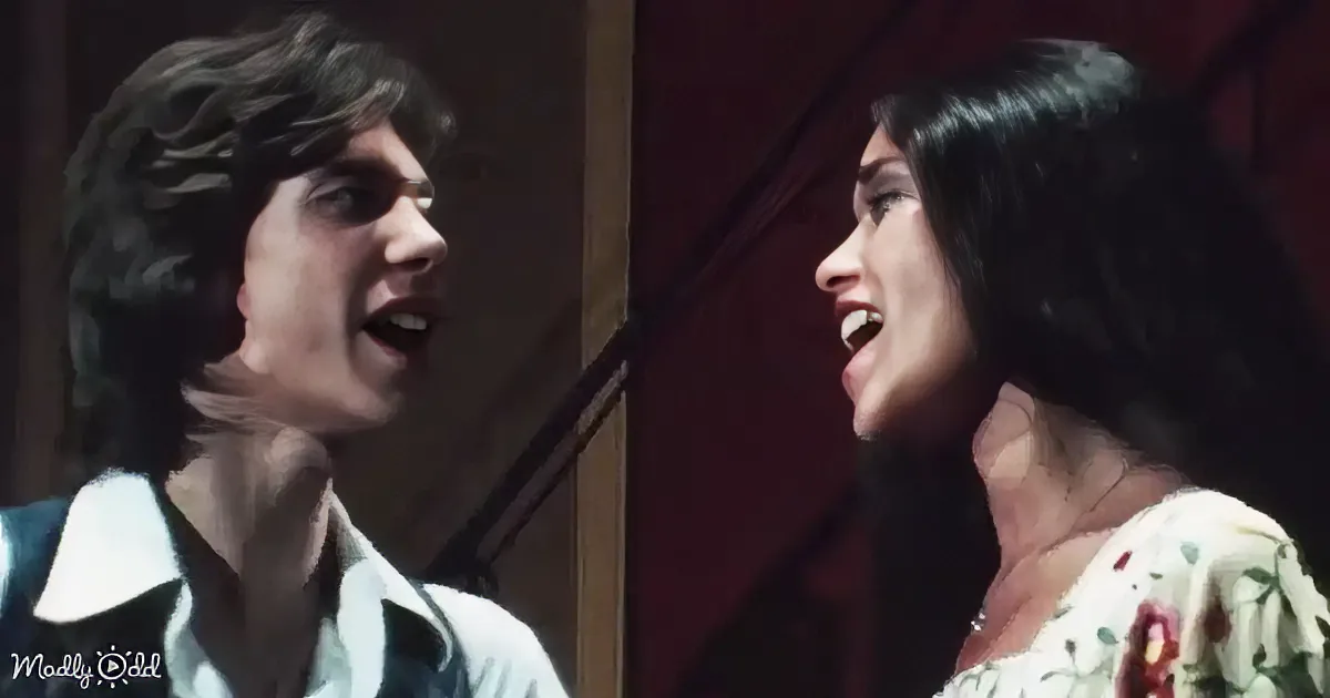 A man and woman are singing passionately, their expressions intense, in a dimly lit setting.