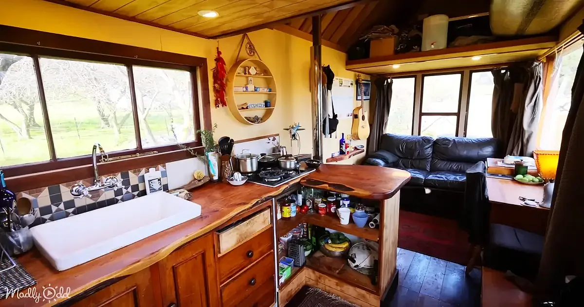 A cozy, rustic kitchen with wooden counters, a white sink, and a view of trees outside.
