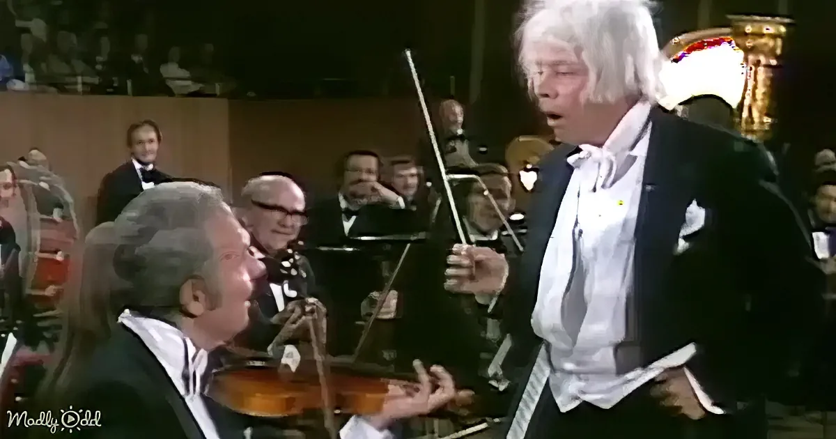 A conductor in a black suit and white shirt is holding a baton, directing an orchestra.