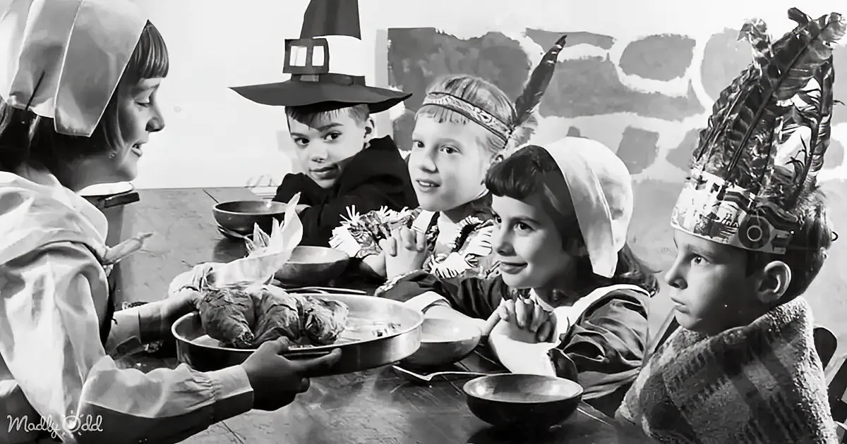 A child in Pilgrim attire holds a roasted turkey, surrounded by children in various costumes at a table.