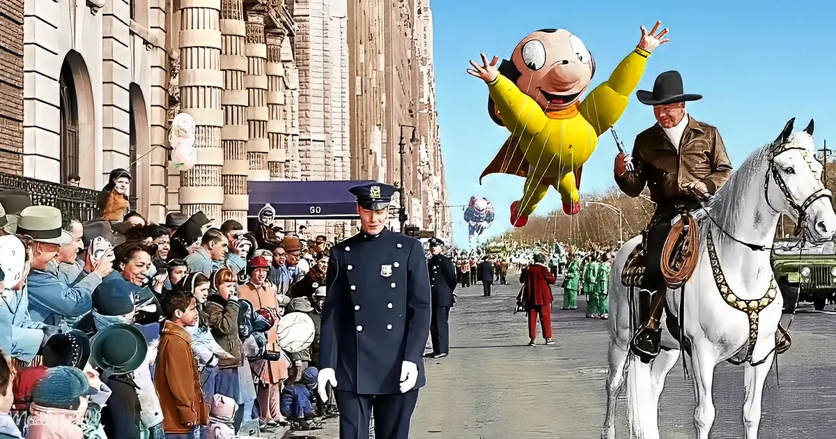 A man in a cowboy outfit rides a white horse in a parade, with a large yellow balloon and crowd watching.