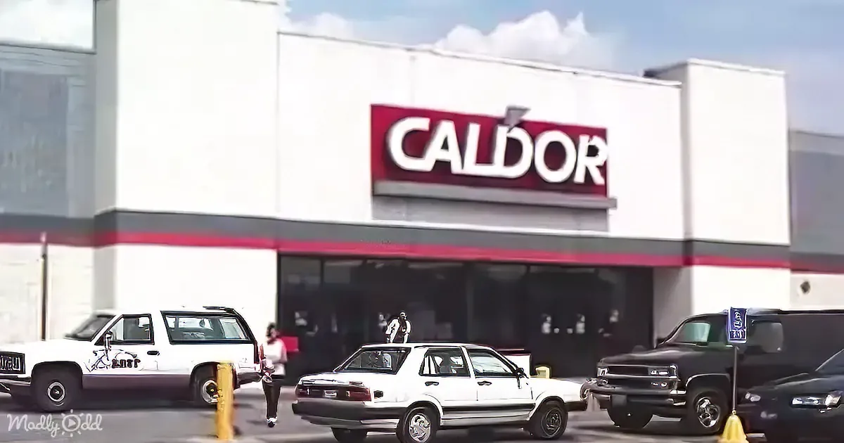 A Caldor store with a red sign, white building, and parked cars in the foreground.
