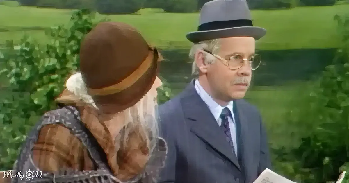 An older man in a suit and hat stands next to a woman in a brown hat and plaid dress, both outdoors.