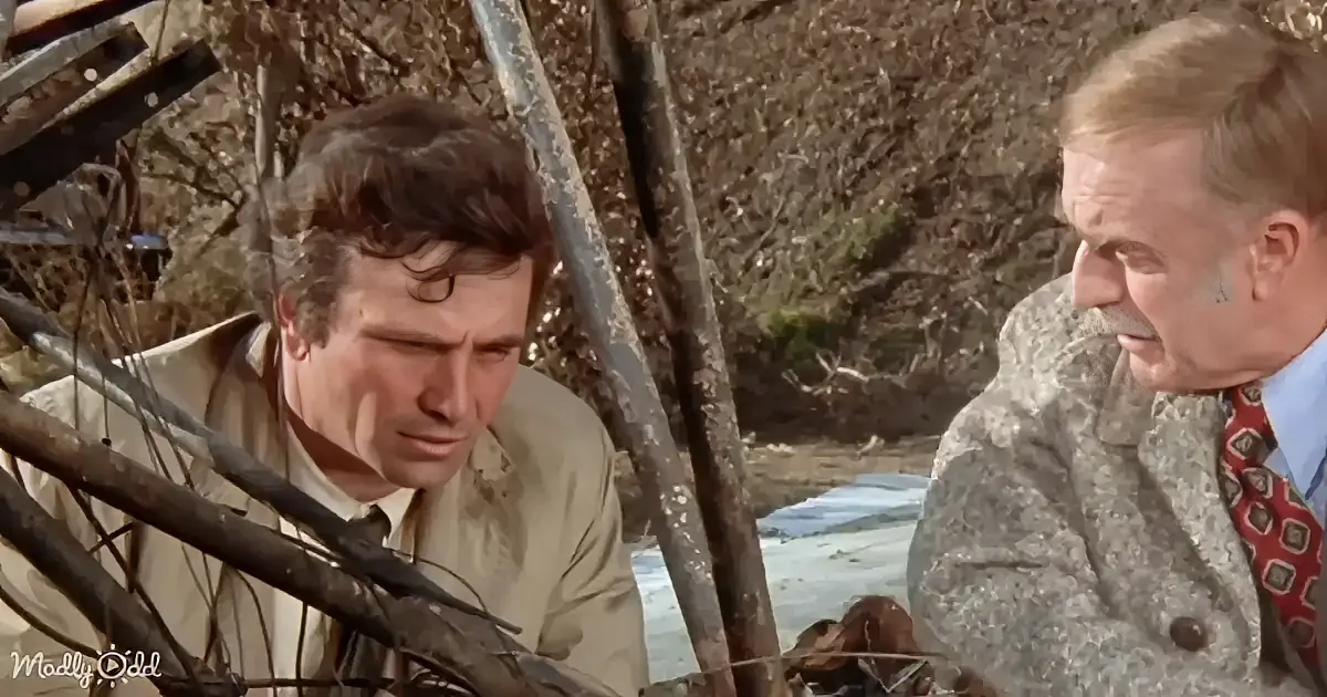 A man with dark, styled hair wearing a beige jacket and white shirt, looking to the side with a serious expression.