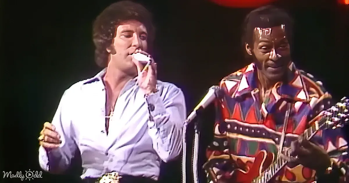 Two men, one holding a microphone, both wearing colorful shirts, appear to be singing or speaking.