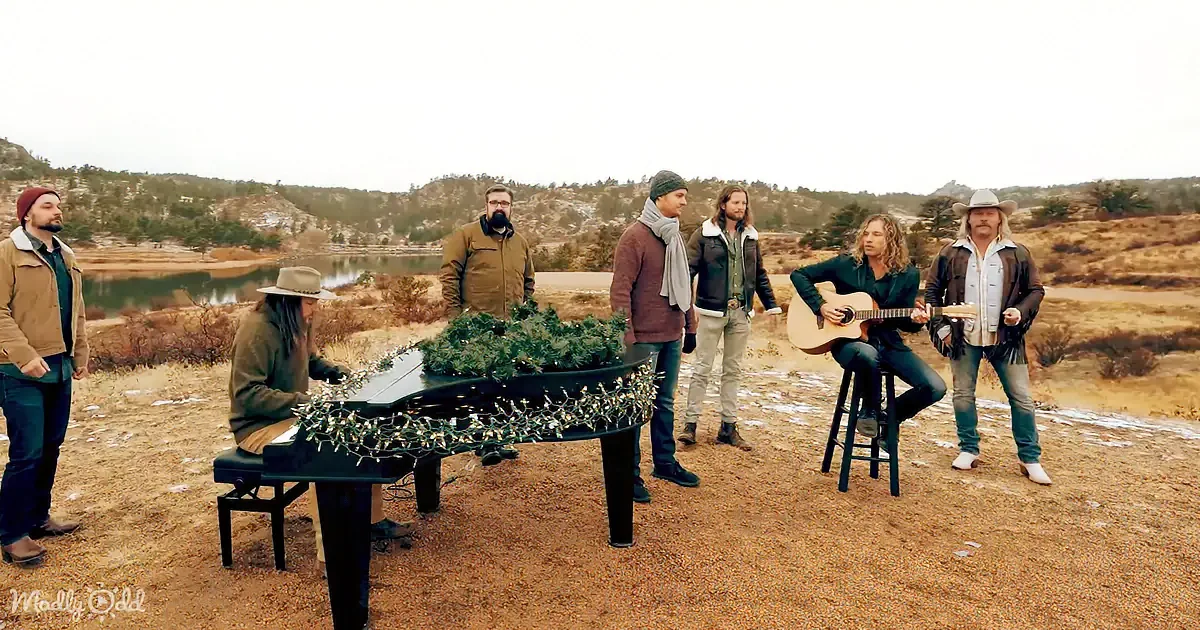 A group of musicians, including a pianist and guitarist, perform outdoors near a lake, surrounded by a scenic, snowy...