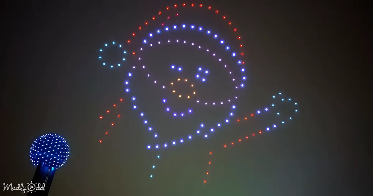 A drone display forms a smiling face with blue and red lights against a dark sky.