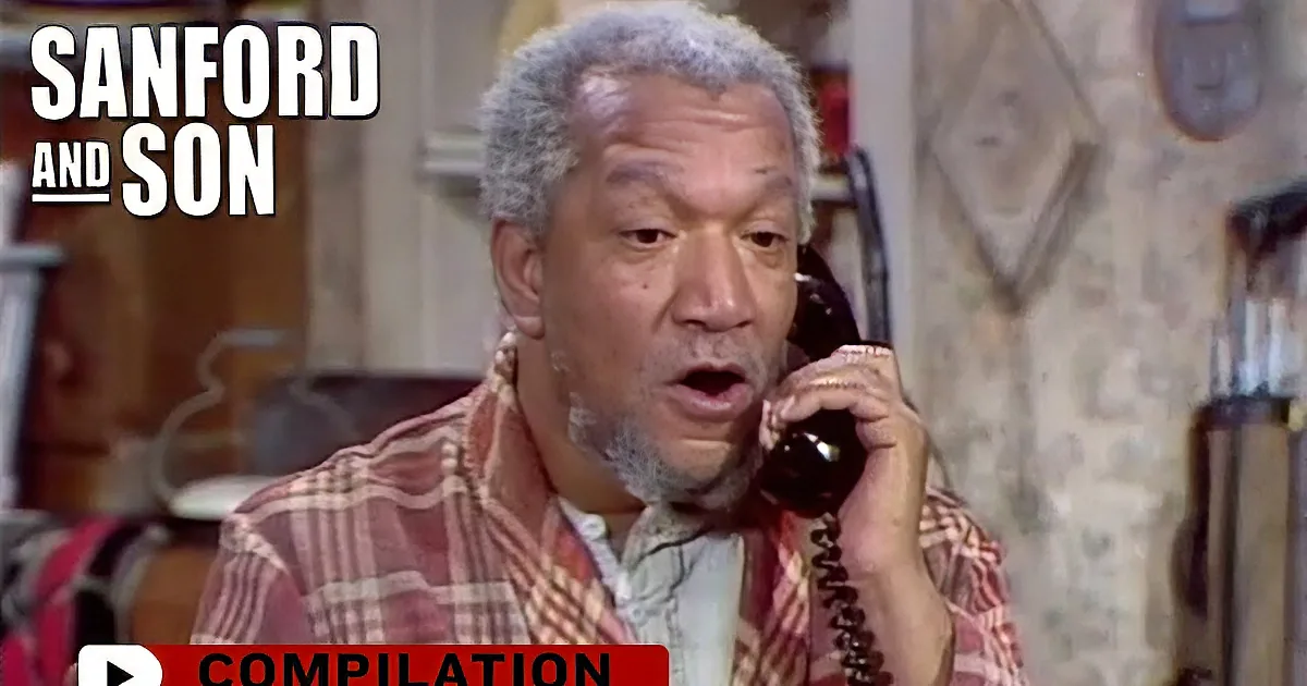 A man in a plaid shirt holds a phone to his ear, appearing to listen intently in a cozy room.