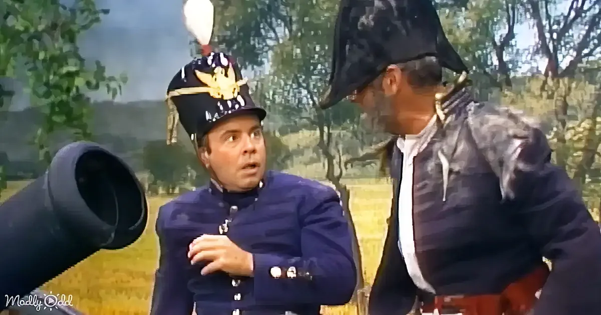 A man in a blue military uniform with a helmet is talking to another man in a dark uniform with a tall hat.