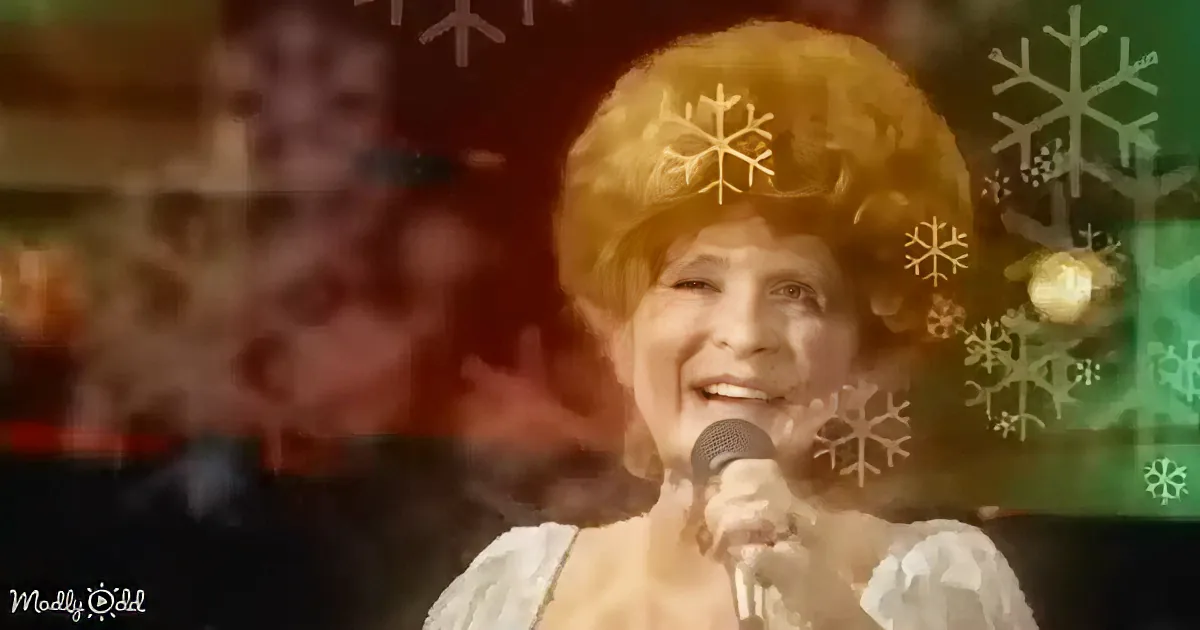 A person wearing a large, fluffy, golden hat with snowflake decorations is singing into a microphone.