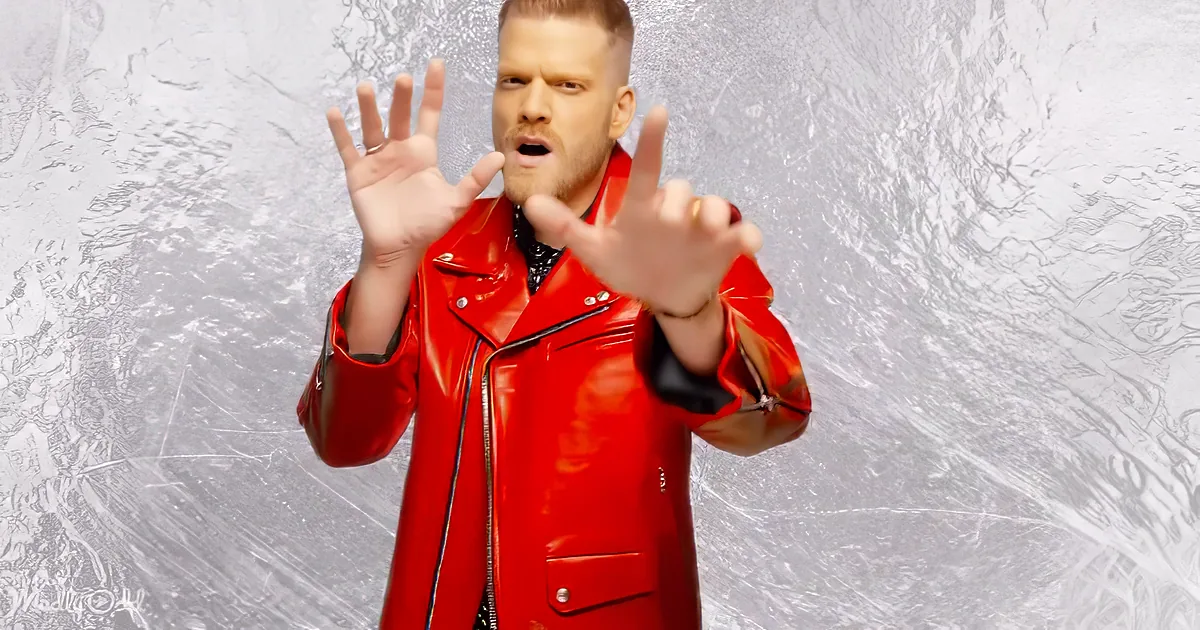 A person in a red leather jacket makes a stop gesture against a textured silver background.