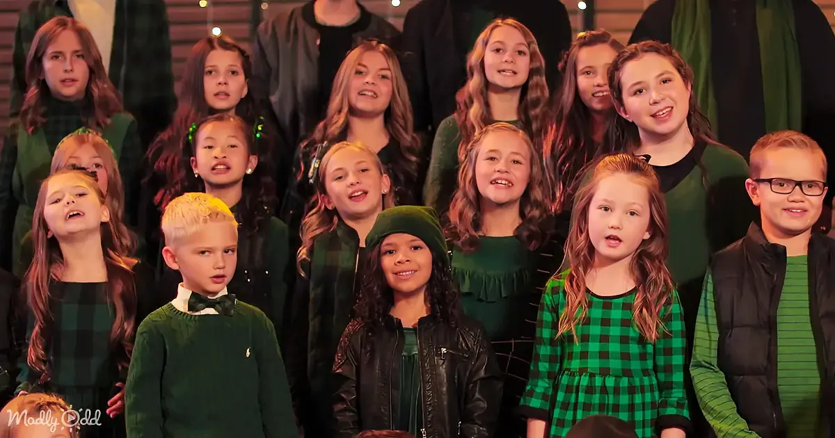 A group of children in green and black attire, smiling and posing together.