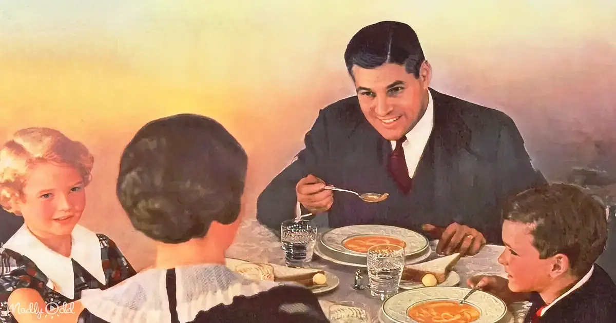 A man in a suit feeds a spoonful of soup to a child at a family dinner table.