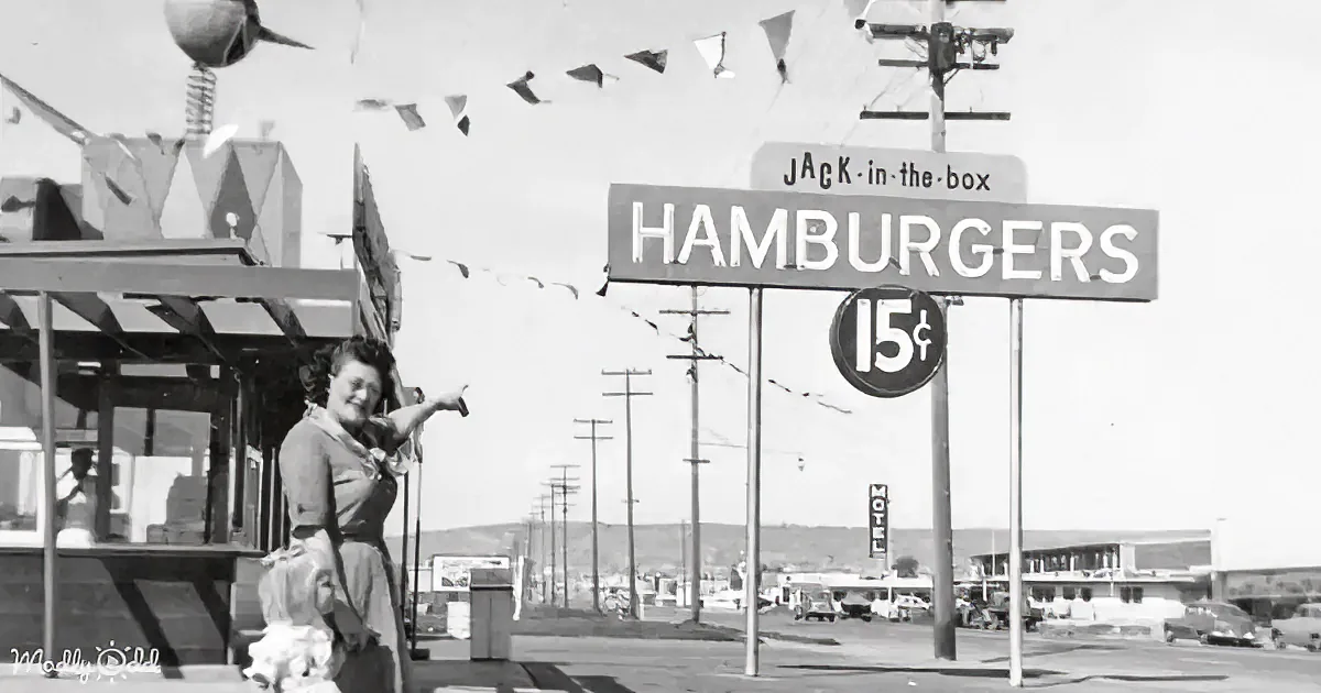 Woman points at Jack-in-the-Box sign advertising hamburgers for 15 cents.