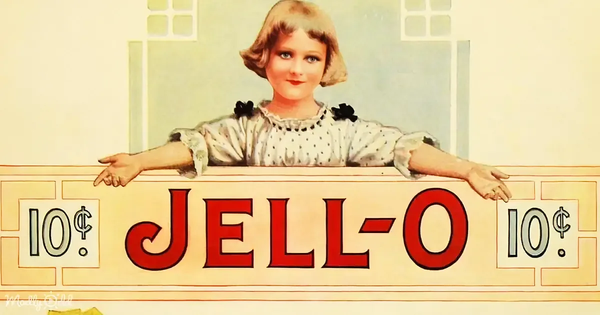 A girl in a polka-dot dress leans on a sign advertising Jell-O for 10 cents.