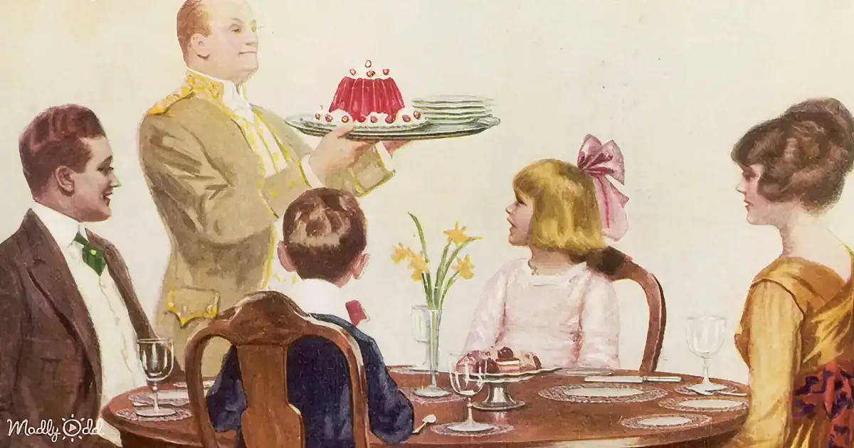 A man in a uniform holds a tray with a dessert, serving it to a family seated around a dining table.