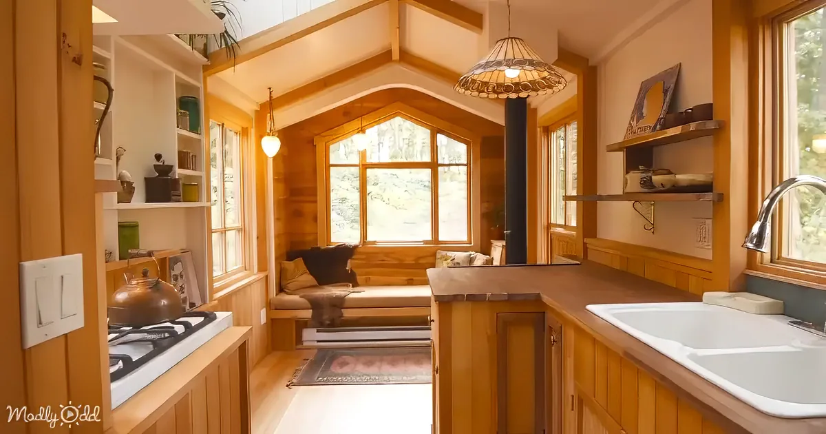 A cozy kitchen with wooden cabinets, a gas stove, a sink, and a window seat with a view.