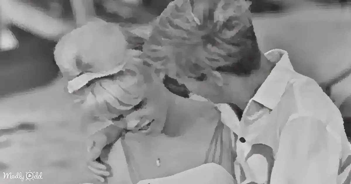 A man and woman are embracing closely, both smiling, in a black-and-white image.