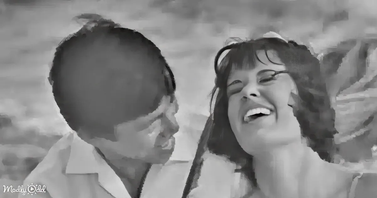 A man and woman share a joyful moment, both smiling and laughing, in a black-and-white image.