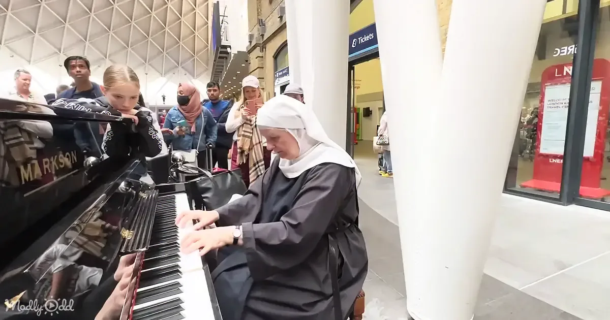 A nun plays a grand piano in a busy public space, surrounded by onlookers.