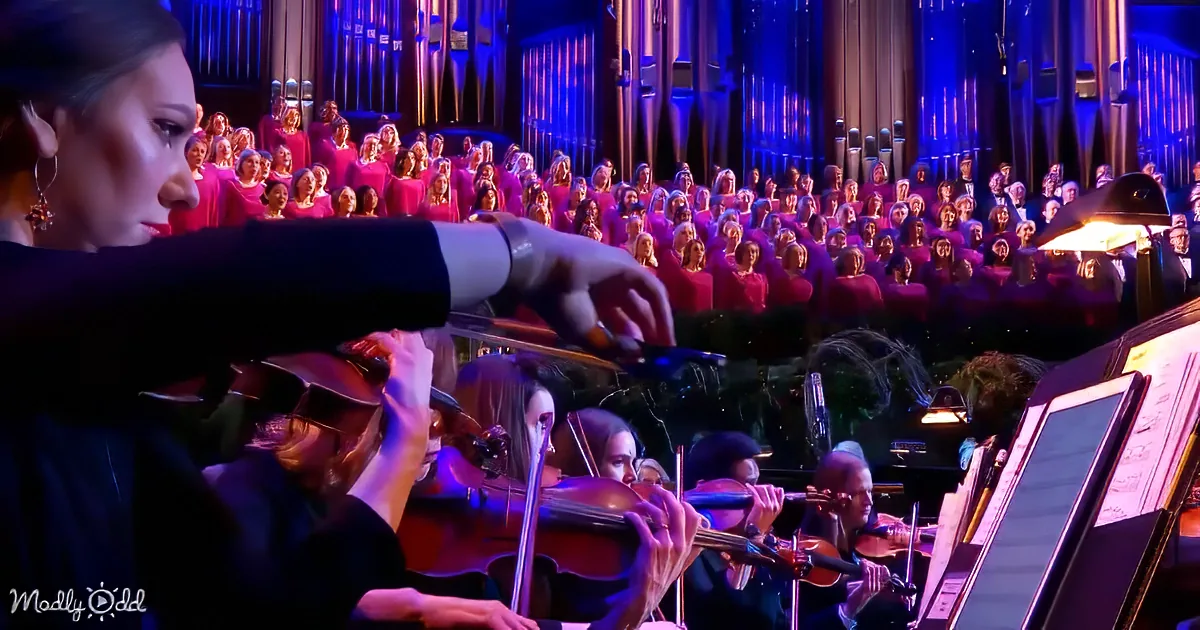 Conductor leads orchestra and choir in a grand performance with vibrant lighting.