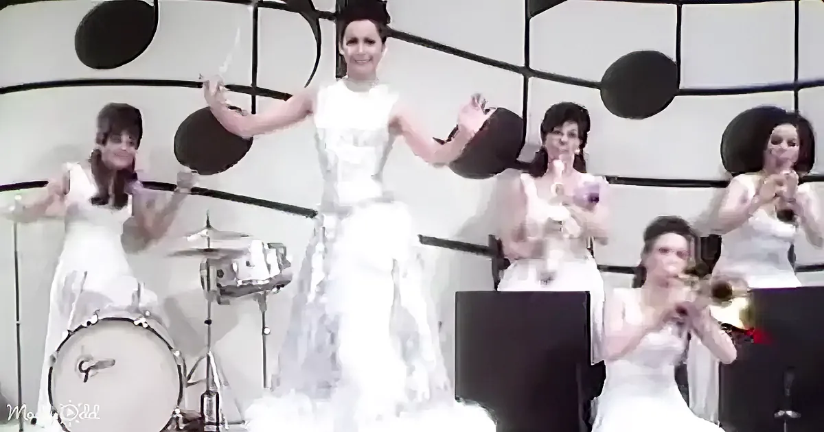 A bride in a white dress is surrounded by musicians in white outfits, playing instruments.