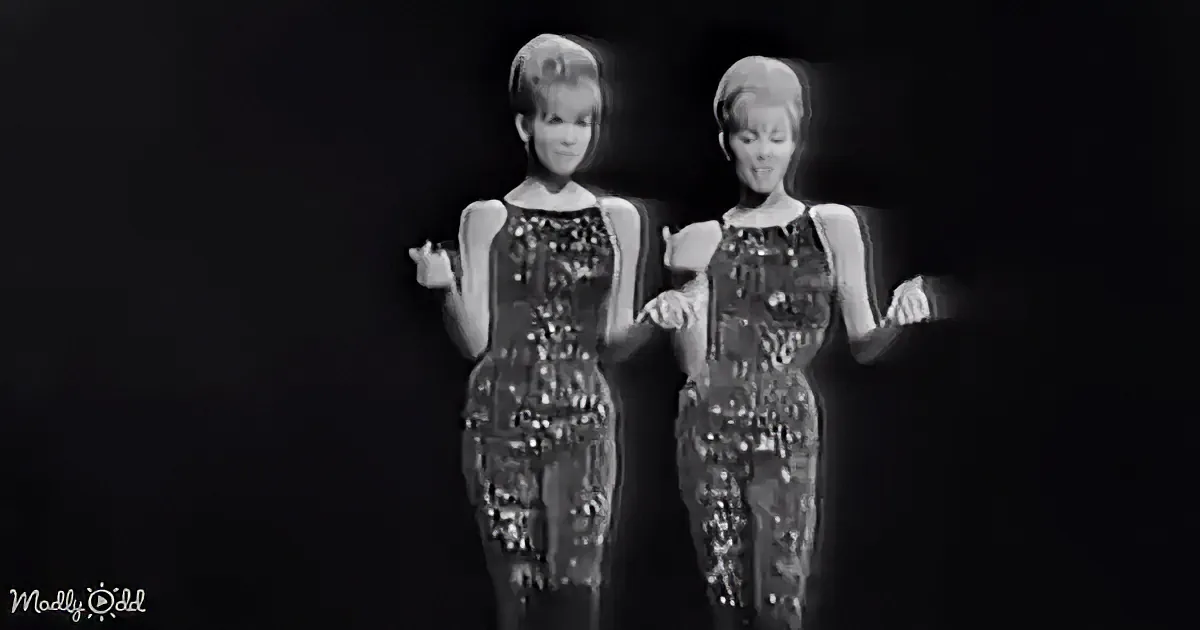 Two identical figures in matching outfits stand side by side against a dark background.