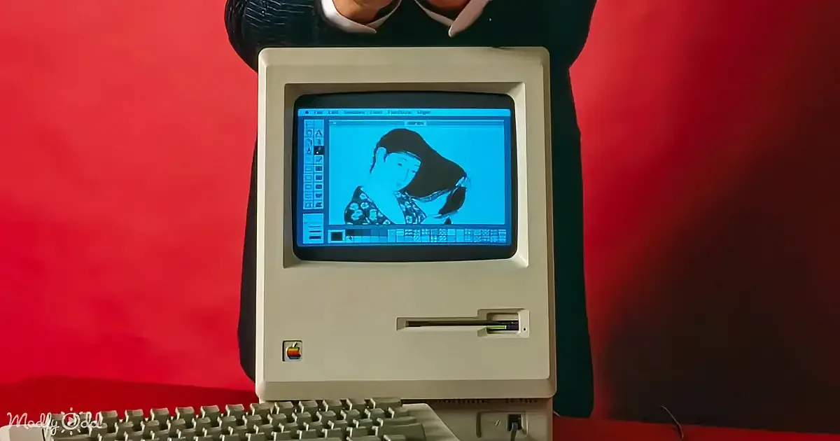A vintage Macintosh computer displays a black-and-white graphic of a woman on its screen.