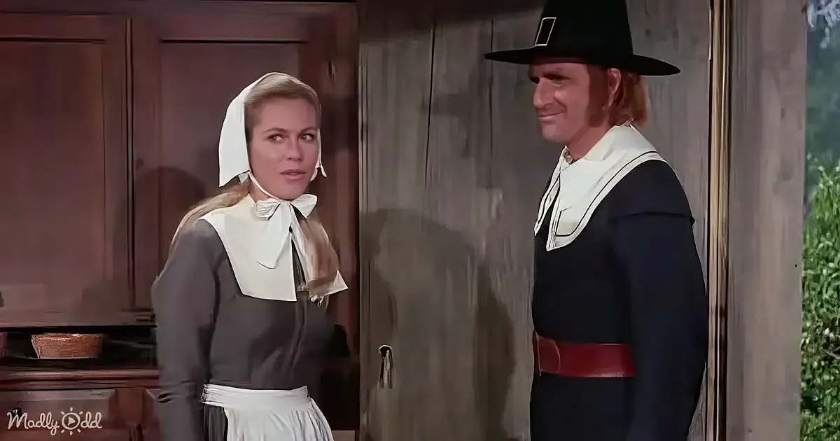 A woman in a white bonnet and dark dress stands beside a man in a black hat and dark outfit, both in a rustic setting.