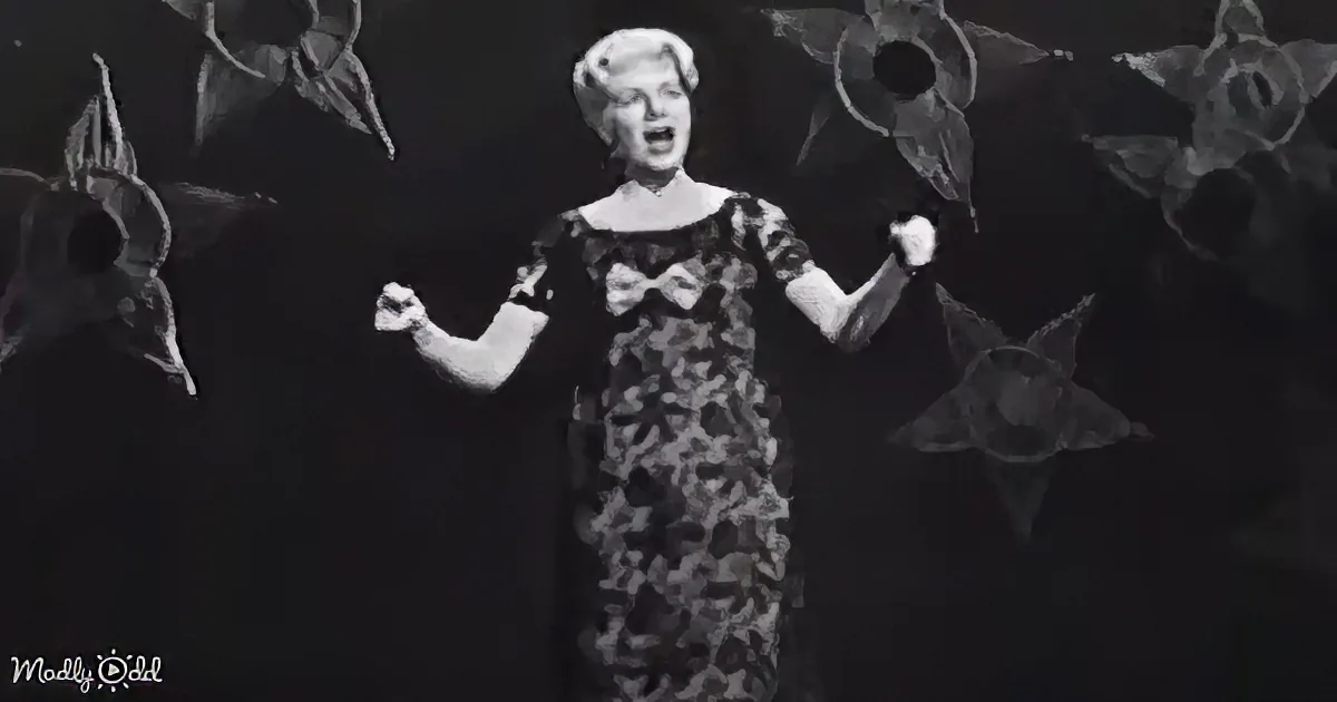 A woman with blonde hair styled in a 1950s fashion, wearing a black and white dress, smiles warmly.