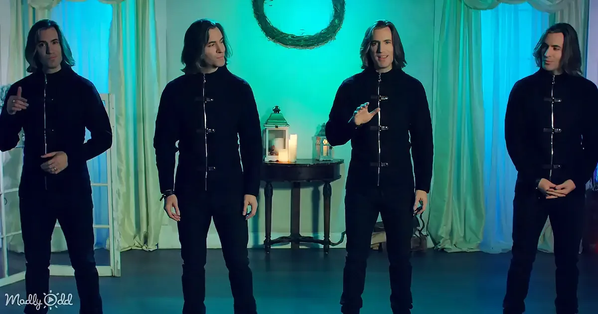 Four identical men in black outfits stand in front of a teal-lit backdrop with a wreath and candles.